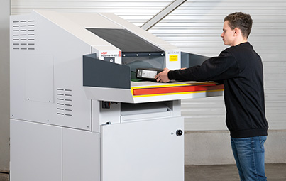 Mann gibt Aktenordner in großen Schredder